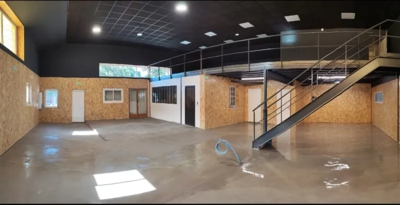 Local professionnel aménagé avec mezzanine métallique, escalier et habillage bois des murs