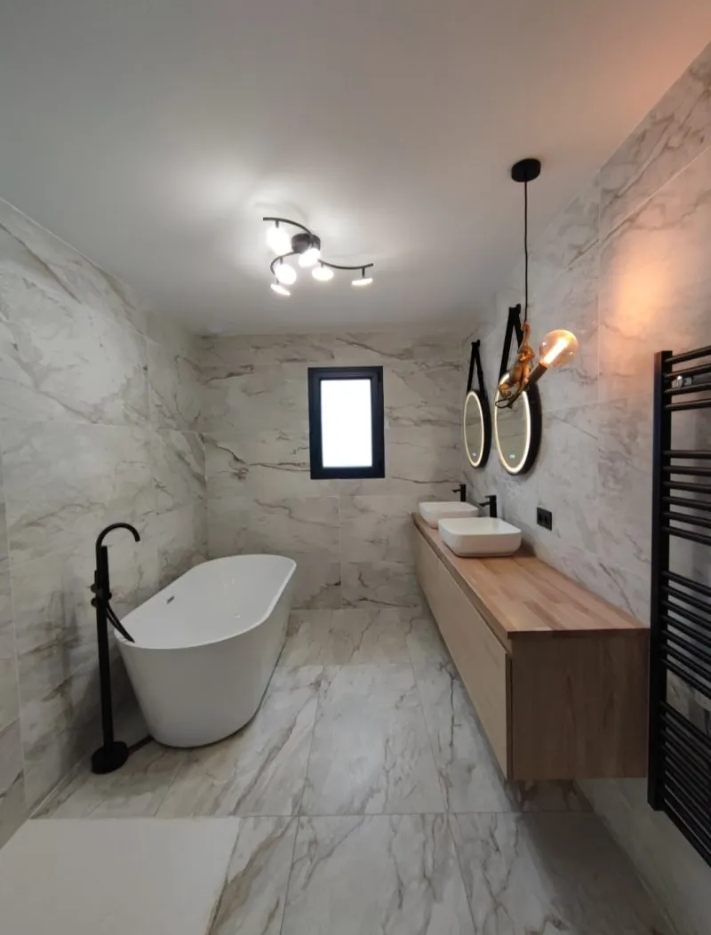 Salle de bains avec baignoire îlot, meuble vasque double en bois et miroirs ronds rétroéclairés