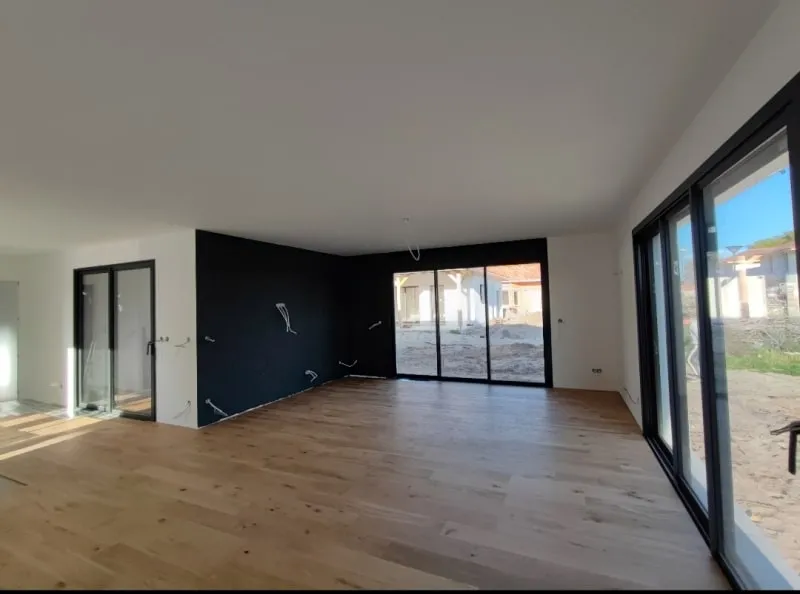 Séjour rénové avec parquet chêne, mur noir et grandes baies vitrées donnant sur le jardin